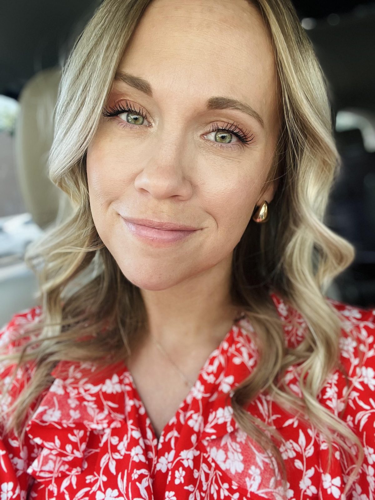 Elise Cole smiling, fair wavy hair, in a red and white floral blouse