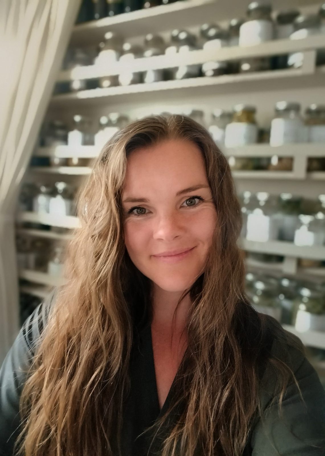 Elisabeth Rowberry standing in front of shelves of apothecary jars