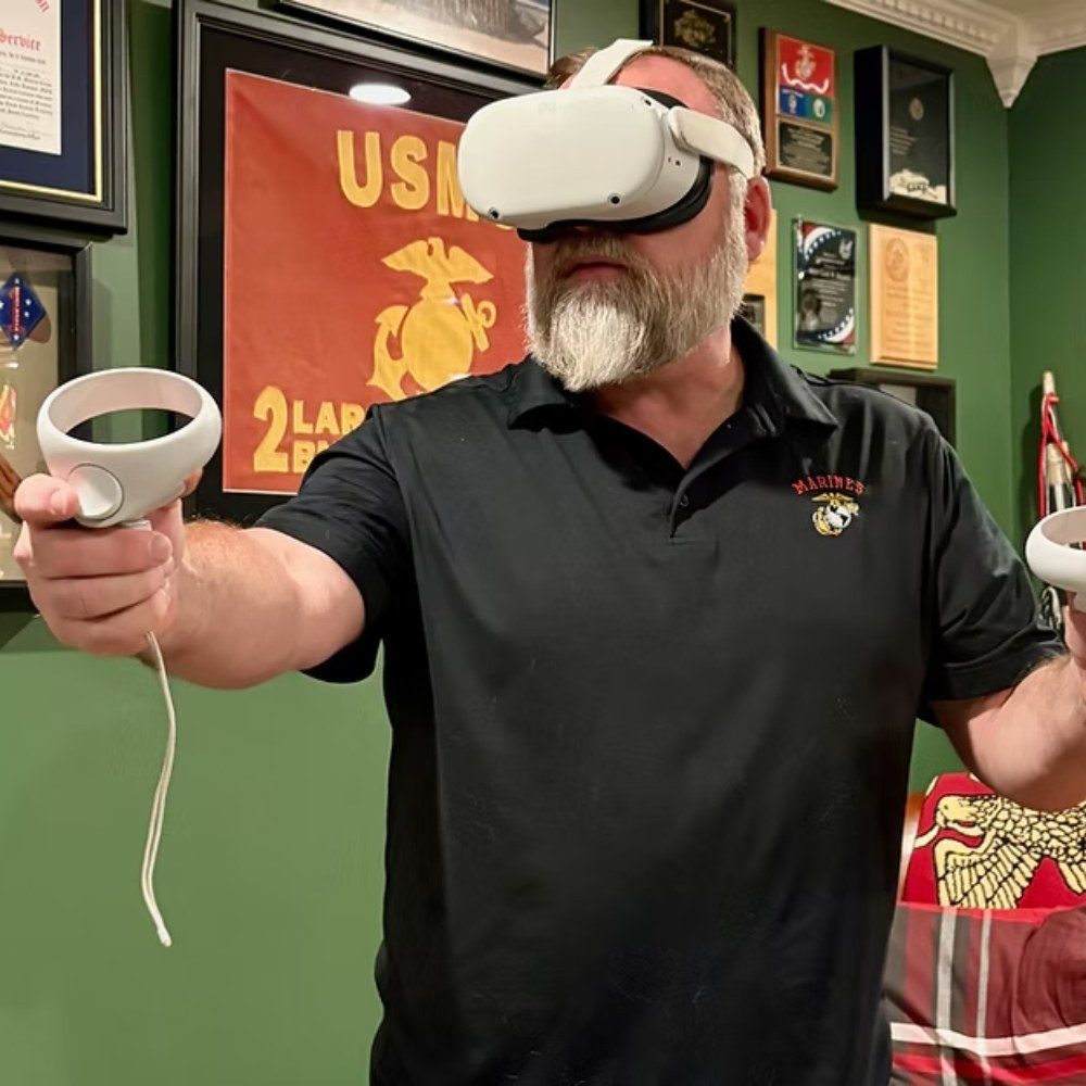 A Marine Corps veteran wearing a virtual reality headset and holding hand controllers