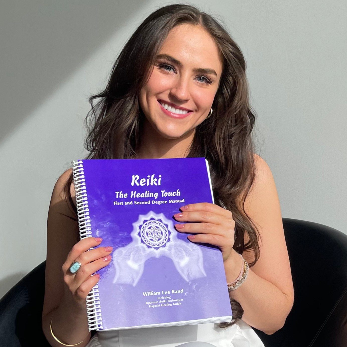 Mariah Law holding her Reiki: The Healing Touch first and second degree manual